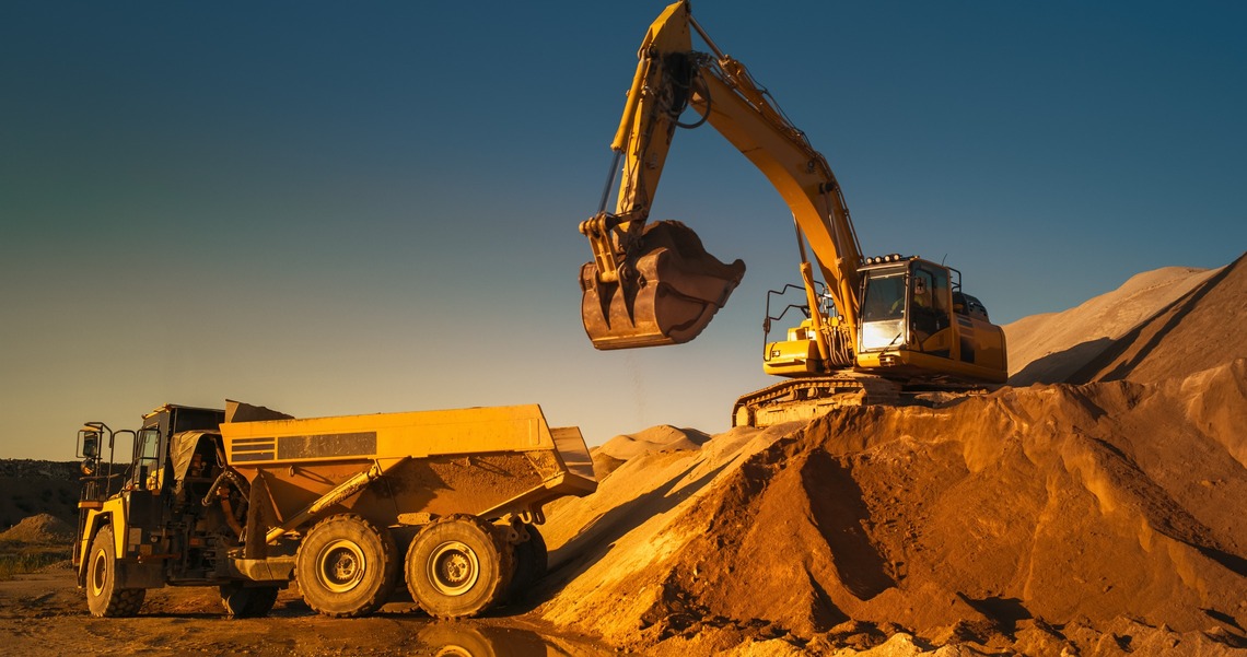 Ein Bagger, der auf einem Sandberg steht und Sand in einen LKW schaufelt. Das Bild zeigt einen Bagger, der auf einem Sandberg steht und Sand in einen LKW schaufelt.