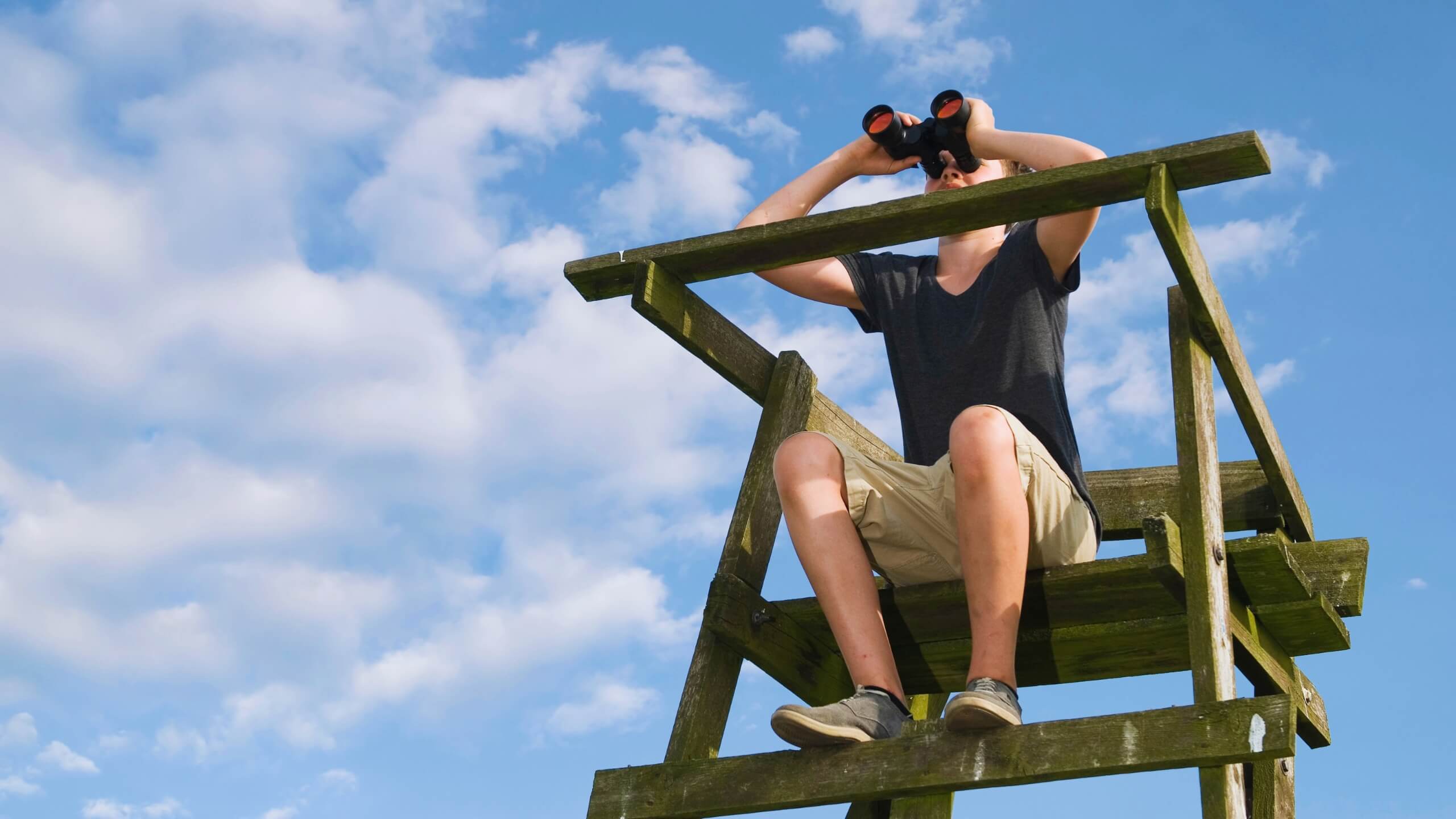 Junger Forstmann auf einem Hochsitz mit Fernglas
